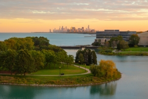University campus bordered by lakefront and urban skyline, illustrating how college environments extend beyond campus boundaries