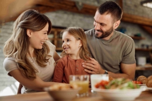 A young child and her parents smiling at each other