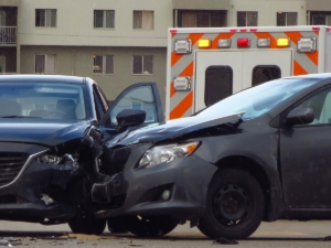 Two heavily damaged cars after a head-on collision with an ambulance responding at the scene